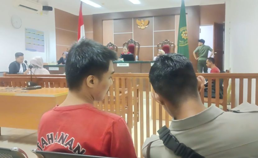 Bripda Ridho sibuk berbicara dengan tahanan Kejari Batam saat persidangan berlangsung di PN Batam